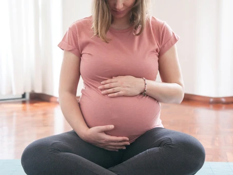 Pregnant woman sitting in a relaxed pose, focusing on her belly, representing pregnancy hematology.