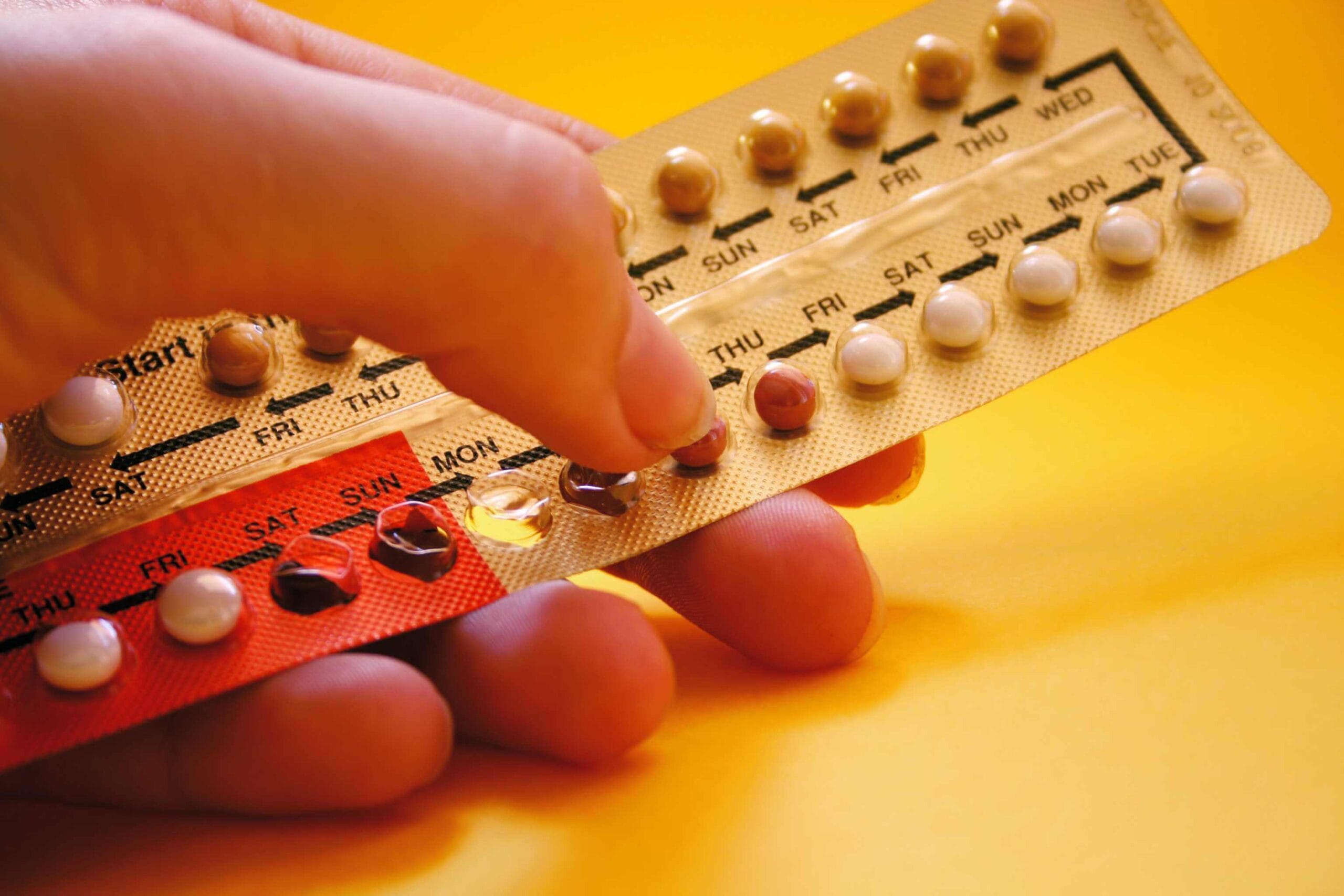 Hand selecting an oral contraceptive pill from a blister pack, highlighting the usage of birth control.