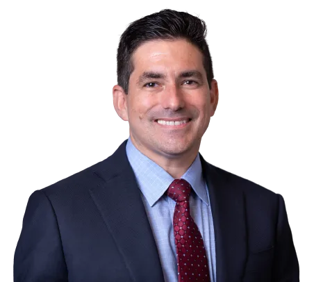 Professional headshot of a smiling man in a suit and red tie.