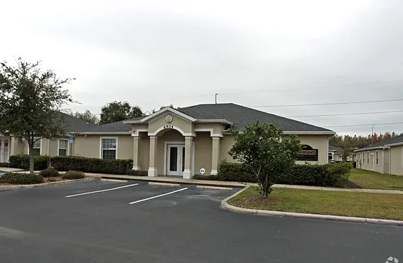 Single-story building with white columns and manicured greenery.