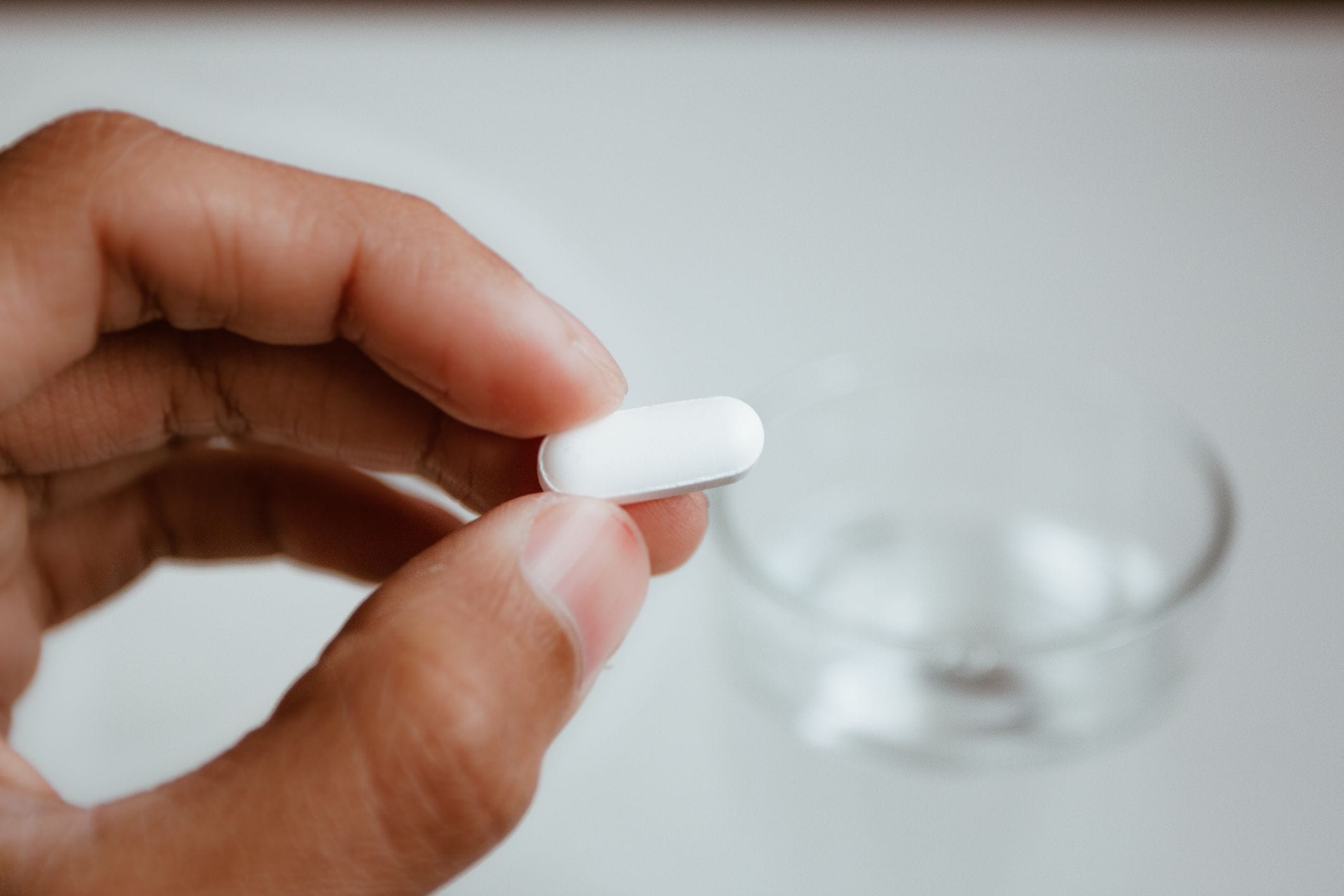Close-up of a hand holding a TXA pill for reducing menstrual bleeding.