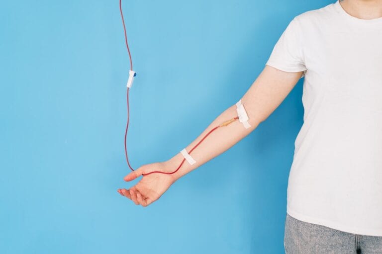 A close-up of a person’s arm with a blood infusion tube, representing the importance of iron infusions.