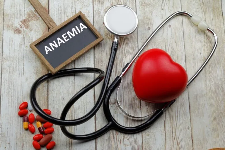 Stethoscope and heart model with "Anemia" sign, illustrating the connection between iron levels and overall health.