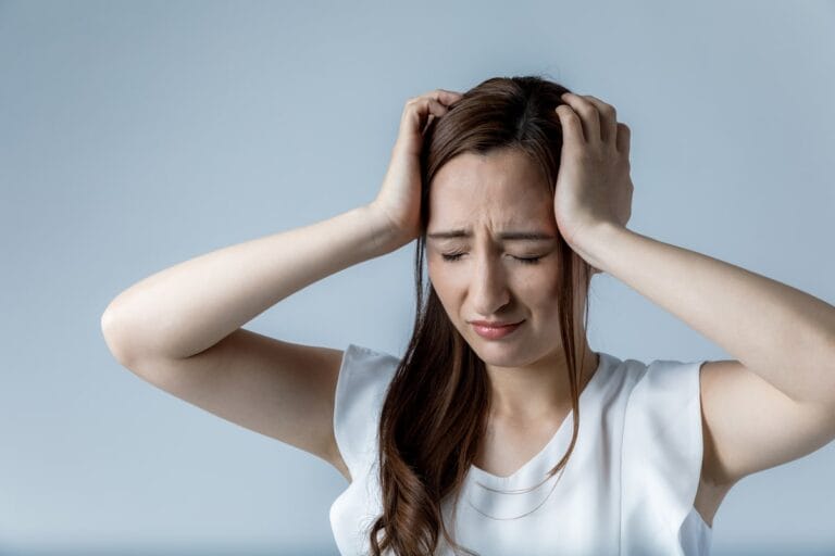 A woman experiencing discomfort, symbolizing the impact of iron deficiency on cognitive function and brain health.
