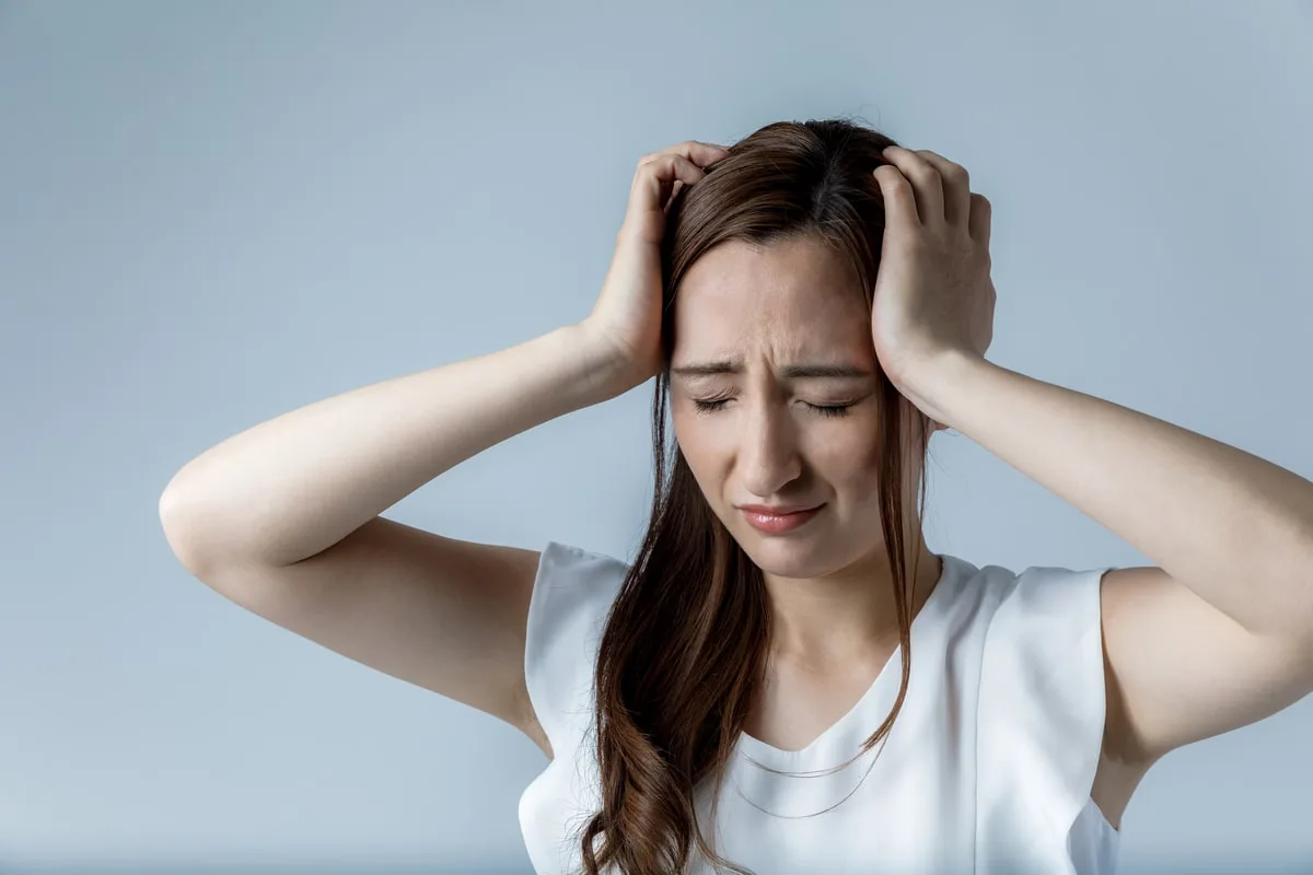 A woman experiencing discomfort, symbolizing the impact of iron deficiency on cognitive function and brain health.