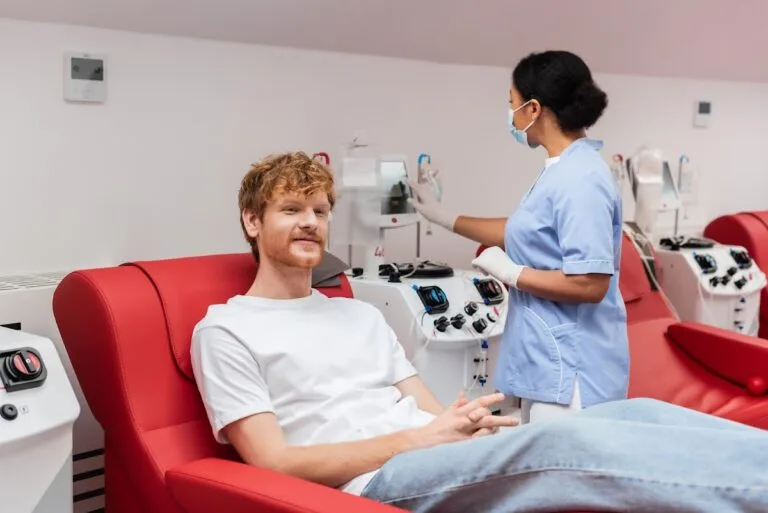 Medical professional in mask and gloves preparing equipment beside patient in modern clinic.