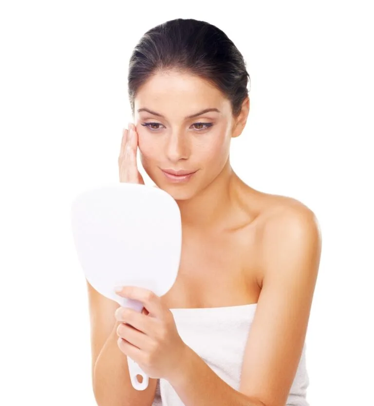 Woman checking face skin in handheld mirror