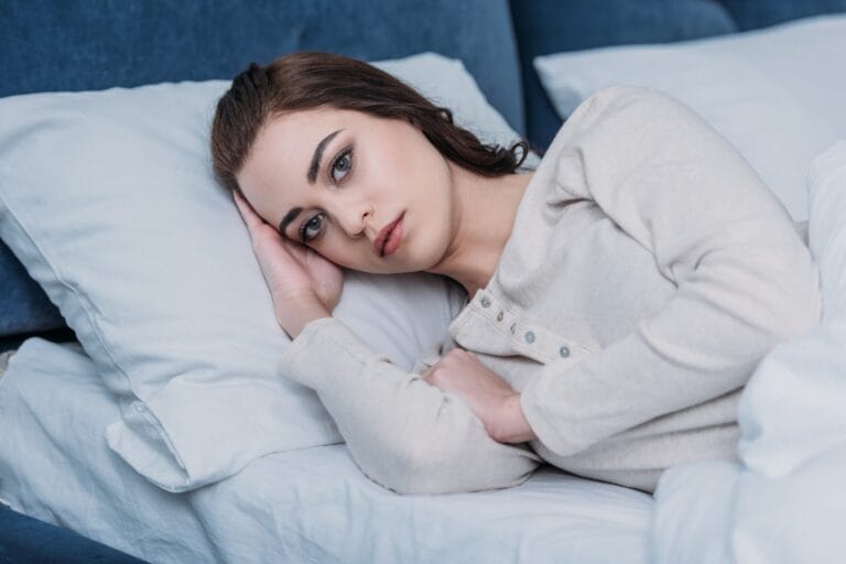 woman lying awake in bed looking worried