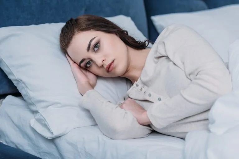 woman lying awake in bed looking worried