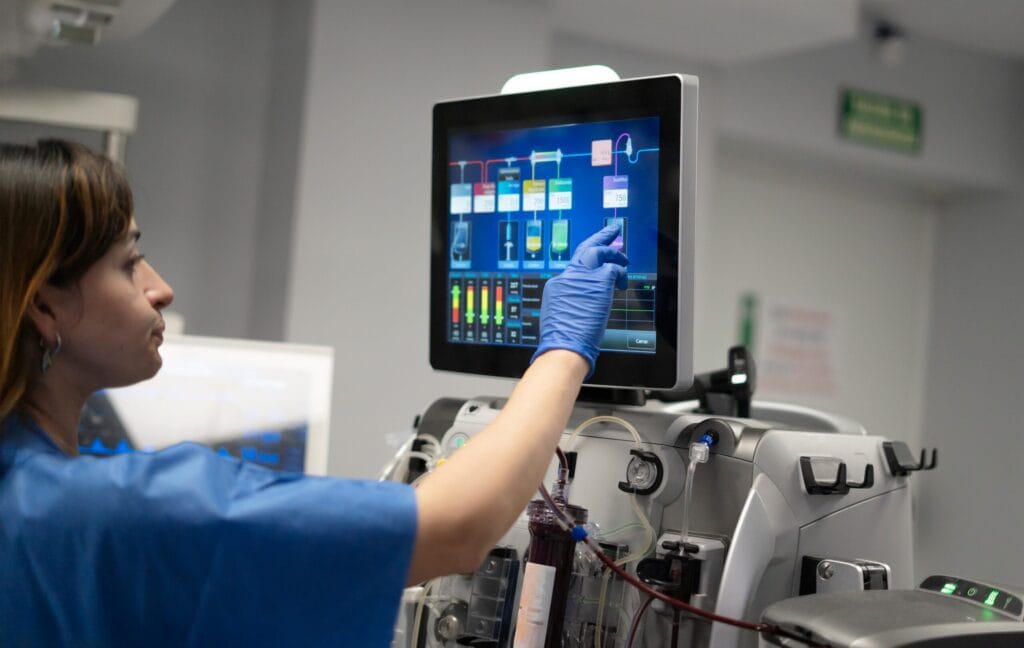 Medical worker using apheresis machine touchscreen
