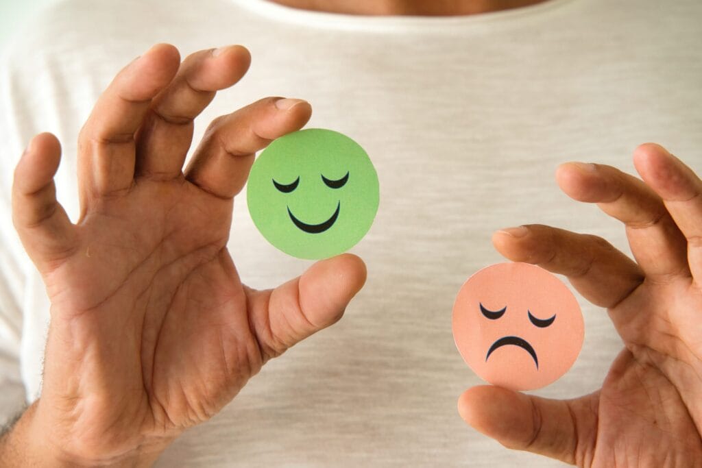 Hands holding happy and sad face icons