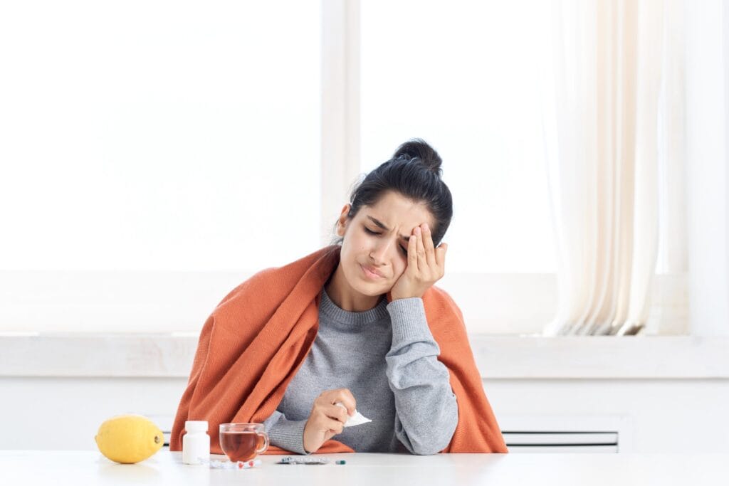 woman with headache wrapped in orange blanket