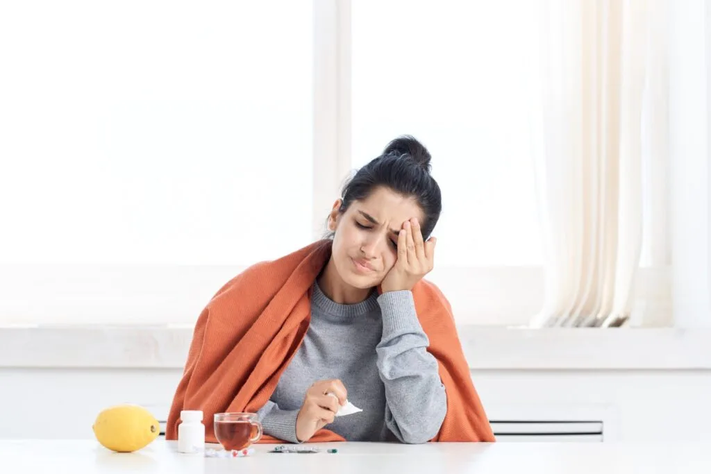 woman with headache wrapped in orange blanket