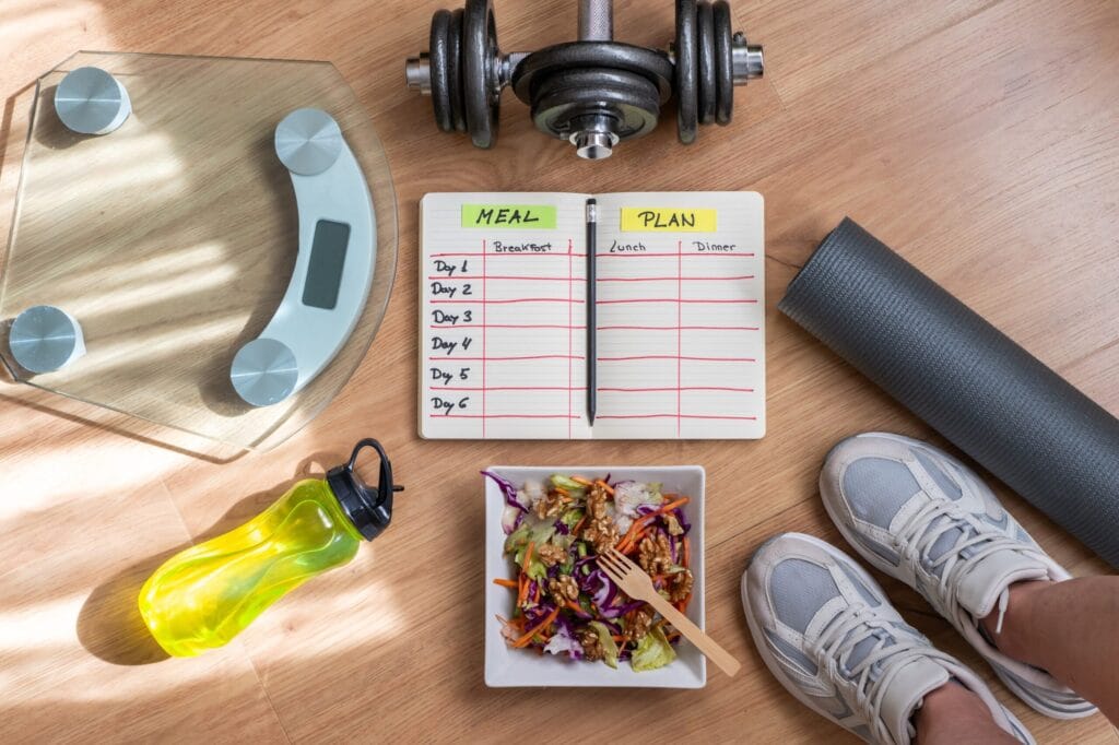 Meal plan notebook with salad and fitness equipment