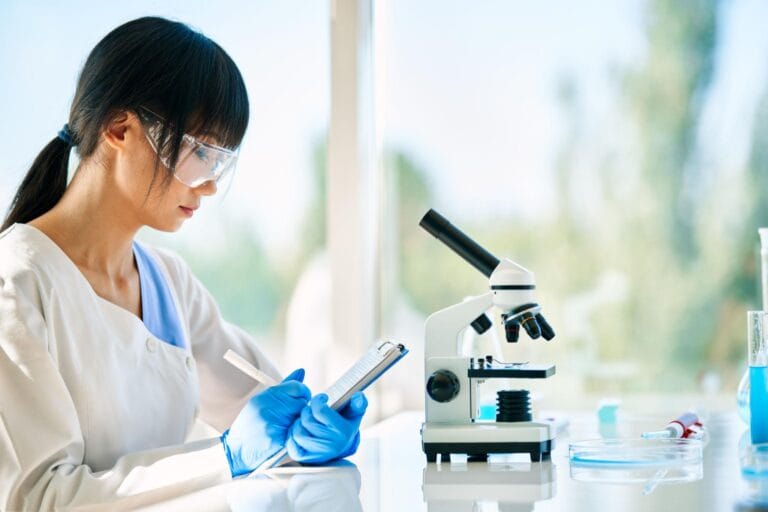 Scientist writing notes near microscope