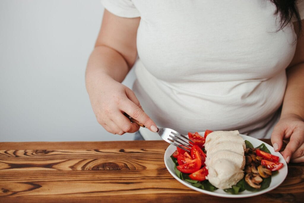 Person eating chicken salad with vegetables