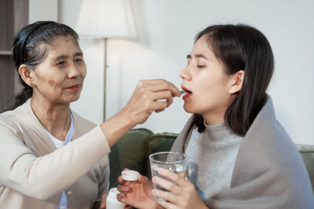 Elderly woman giving pill to young woman